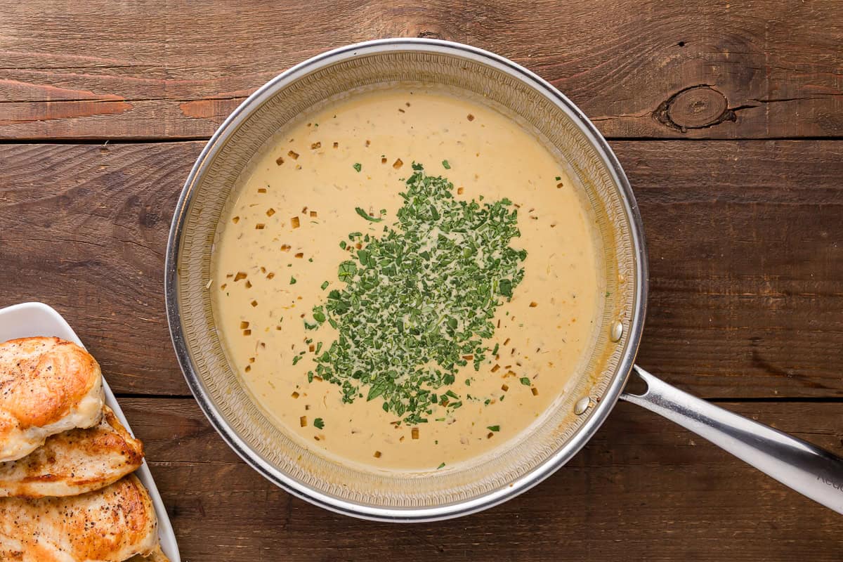 adding cilantro to lime cream sauce in a skillet.
