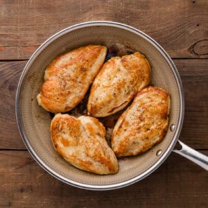 four seared chicken breasts in a skillet.