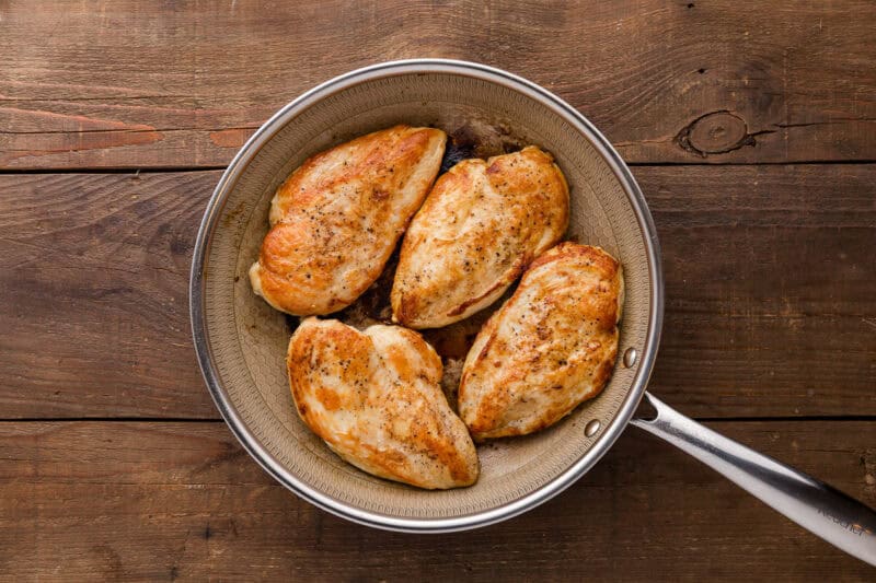 four seared chicken breasts in a skillet.