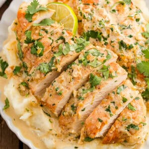 overhead view of a sliced creamy cilantro lime chicken breast on a plate with mashed potatoes.