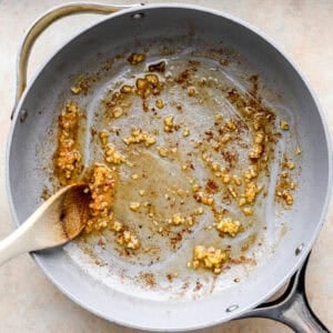 sautéeing garlic in a pan with a wooden spoon.