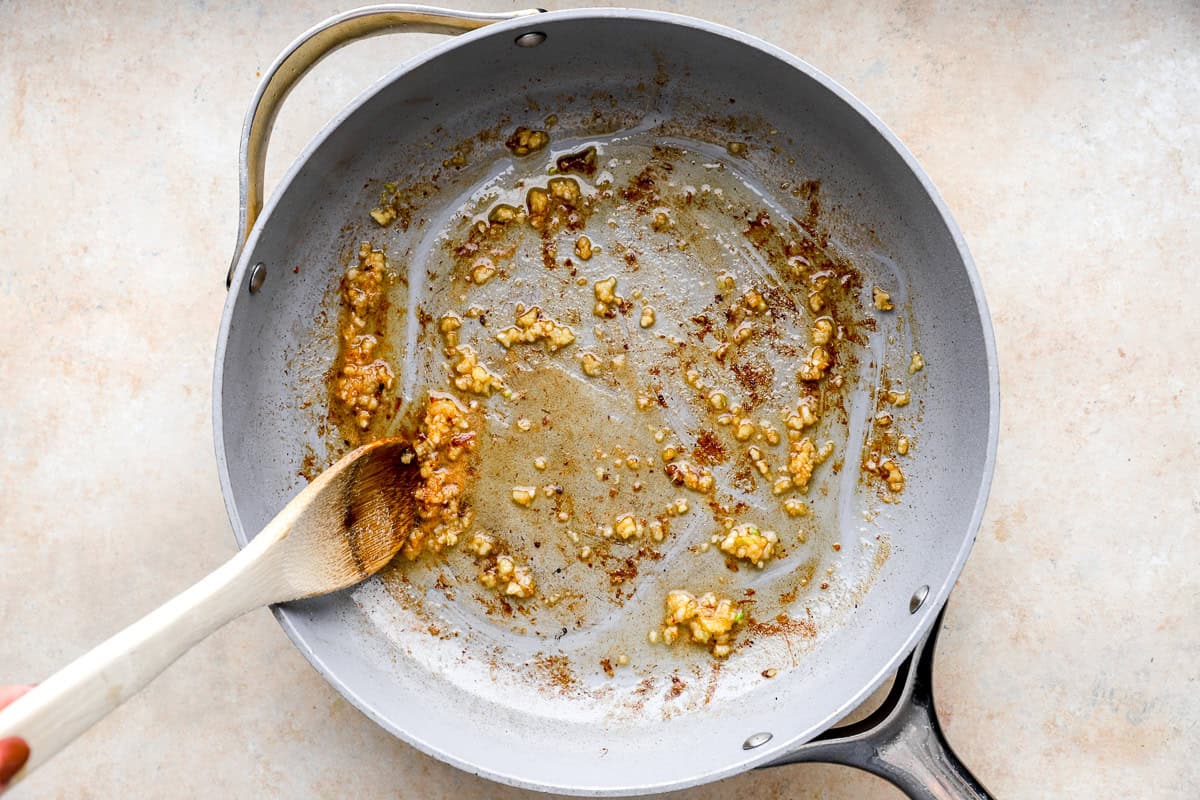 sautéeing garlic in a pan with a wooden spoon.