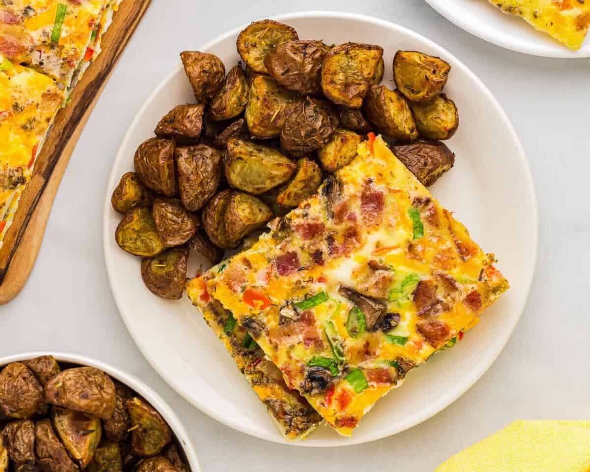 overhead view of a serving of sheet pan eggs on a white plate with potatoes.