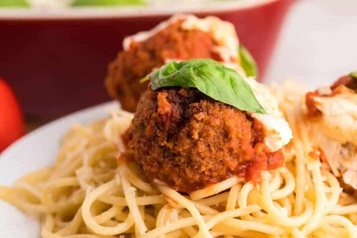 spaghetti noodles topped with 2 chicken parmesan meatballs