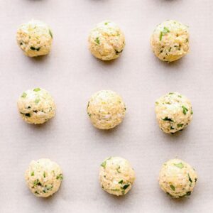 raw Indian chicken meatballs on a baking sheet.