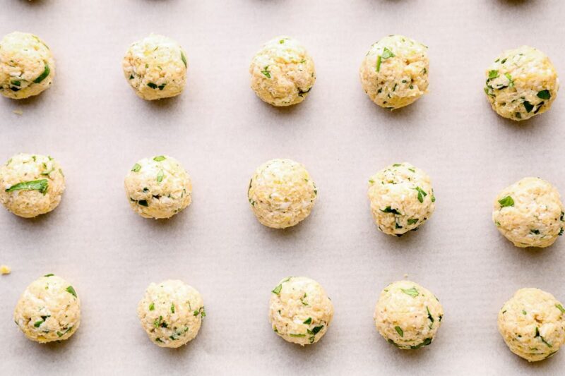 raw Indian chicken meatballs on a baking sheet.