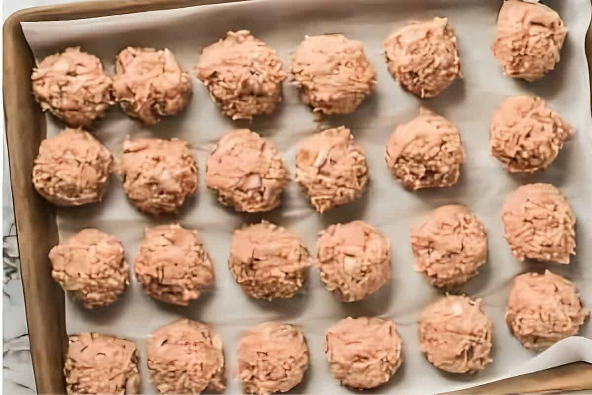 Ground chicken meatballs arranged on a baking sheet.