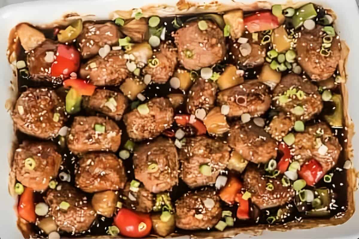 Baked Hawaiian chicken meatballs, garnished with sesame seeds and green onions.