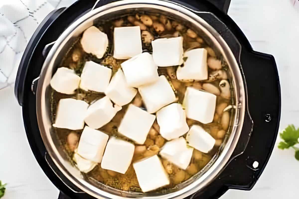 Cubes of cream cheese added to an Instant Pot.