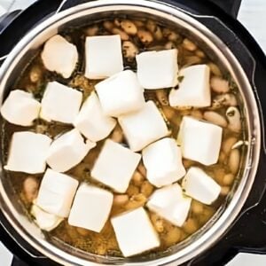 Cubes of cream cheese added to an Instant Pot.