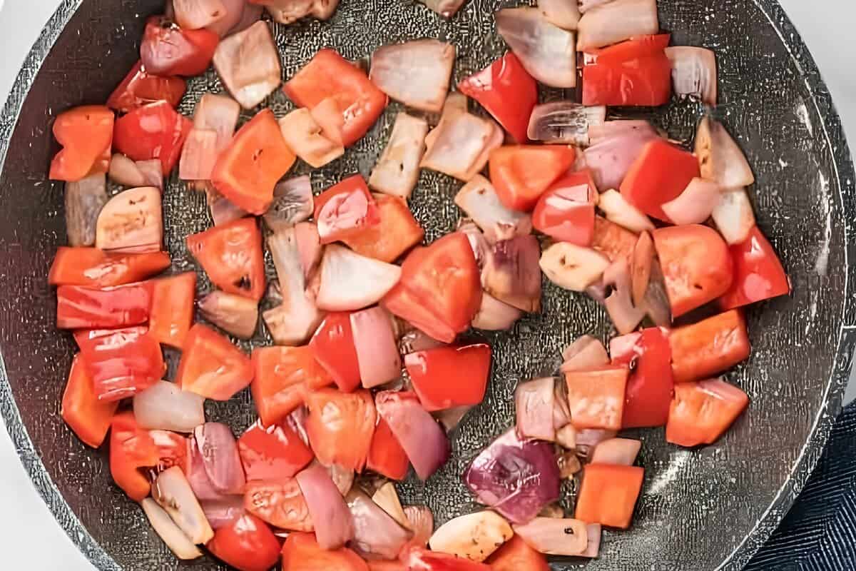 Chopped peppers and onions cooking in a skillet.