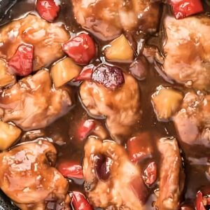 Chicken thighs, pineapple, peppers, and onions cooking in sauce.
