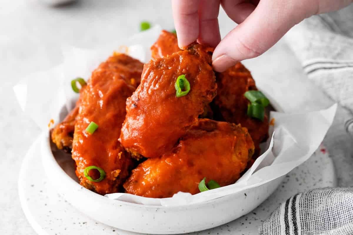 grabbing an air fryer nashville hot wing from a bowl.