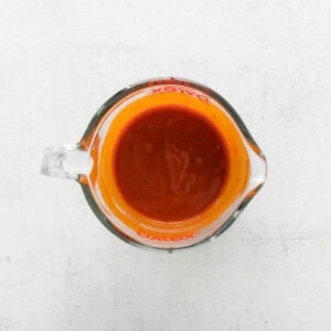nashville hot sauce in a glass liquid measuring cup.
