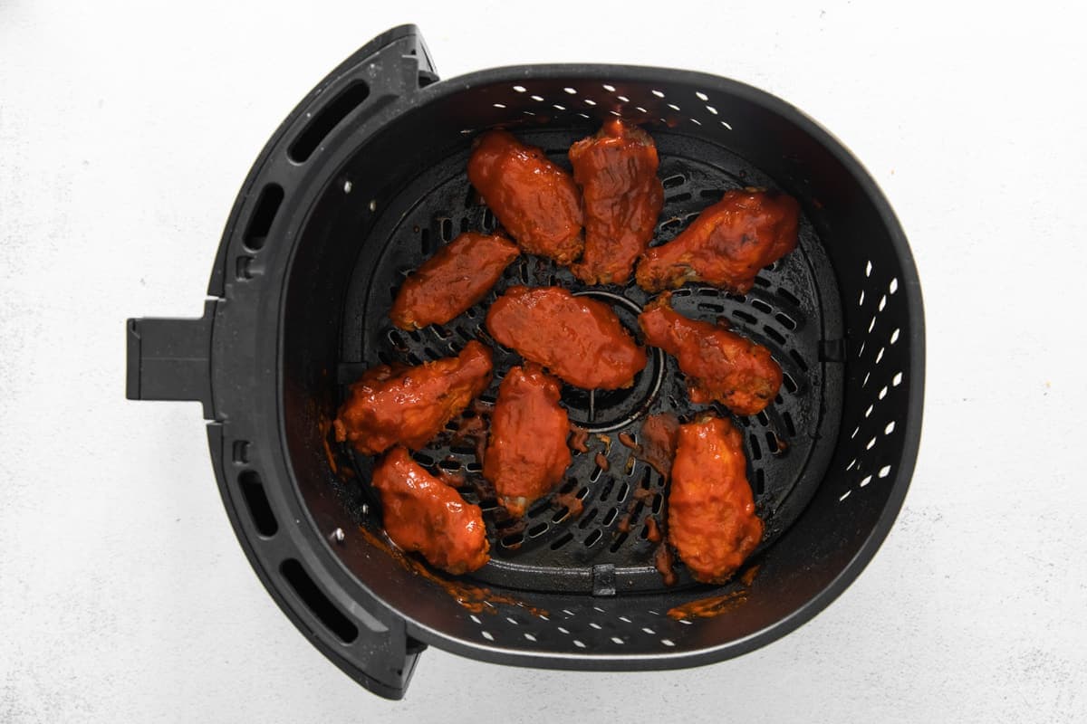 nashville hot chicken wings in an air fryer basket.