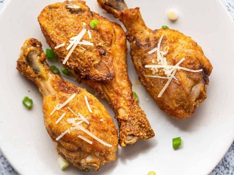 up close air fryer garlic parmesan chicken drumsticks on white plate