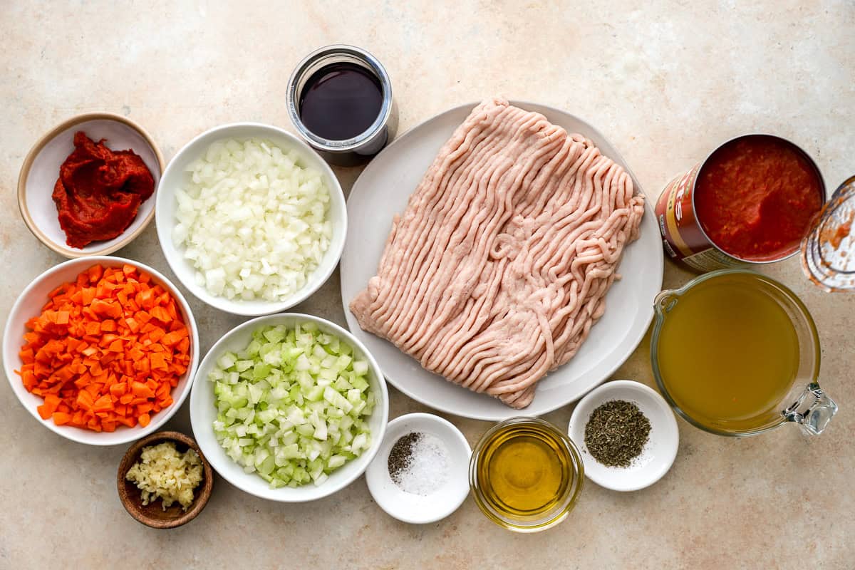 portioned ingredients for chicken bolognese in individual bowls.