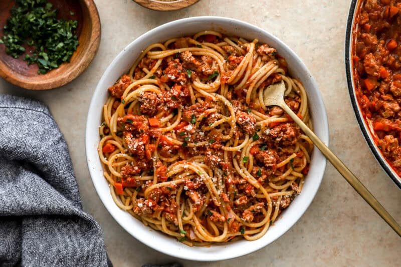 overhead view of a bowl of chicken bolognese pasta with a fork.