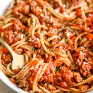 a bowl of chicken bolognese pasta with a fork.