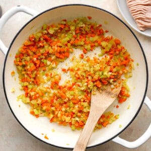 sauteeing mirepoix in a dutch oven with a wooden spoon.