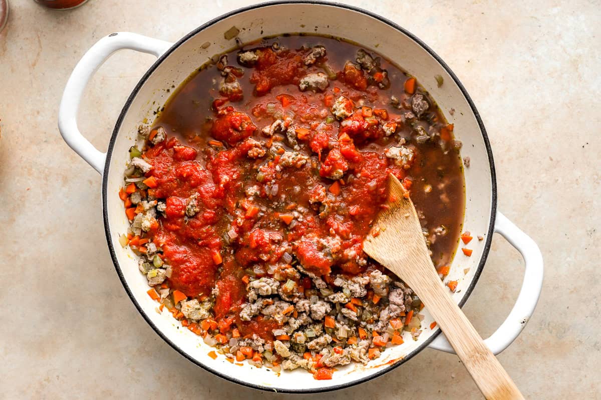 stirring tomatoes and tomato paste into cooked ground chicken and veggies in a dutch oven.