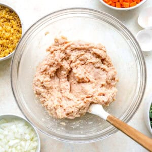 ground chicken meatball mixture in a glass bowl with a rubber spatula.
