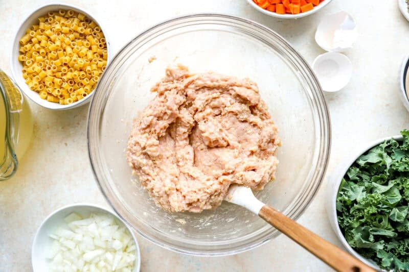 ground chicken meatball mixture in a glass bowl with a rubber spatula.