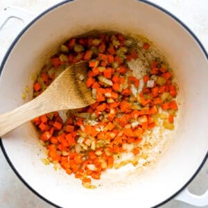 sauteeing mirepoix in a Dutch oven with a wooden spoon.