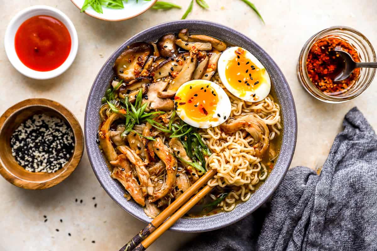 overhead view of a bowl of chicken ramen with a boiled egg, green onions, and chopsticks.