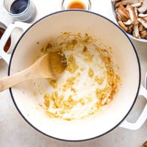 sautéeing ginger and garlic in a dutch oven with a wooden spoon.