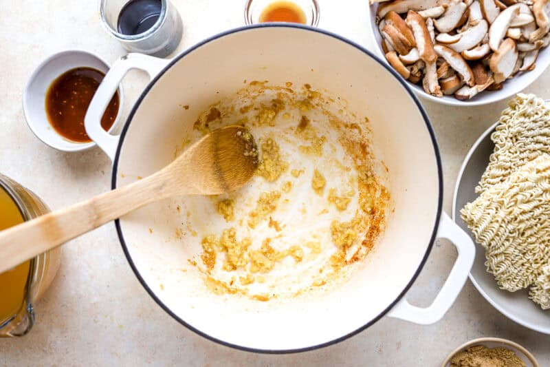 sautéeing ginger and garlic in a dutch oven with a wooden spoon.