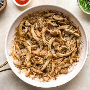 sautéeing shredded chicken in a skillet.