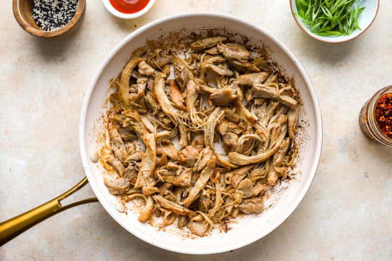 sautéeing shredded chicken in a skillet.