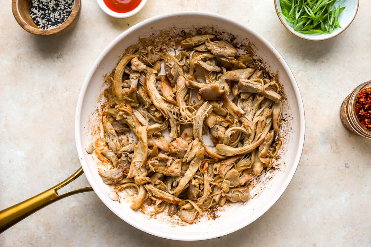 sautéeing shredded chicken in a skillet.