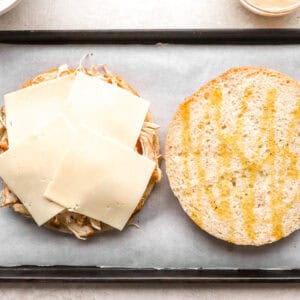 a large focaccia round topped with shredded chicken and cheese.