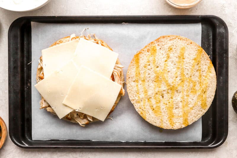 a large focaccia round topped with shredded chicken and cheese.