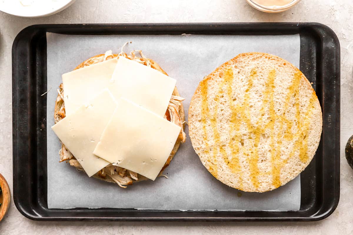 a large focaccia round topped with shredded chicken and cheese.