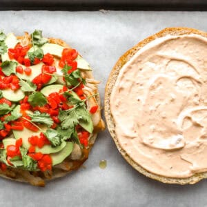 a halved focaccia round topped with shredded chicken, cheese, avocado, pimentos, and cilantro; chipotle mayo on the other half.