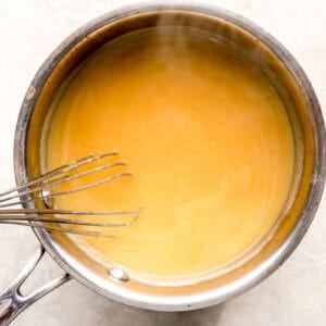 chicken broth gravy in a saucepan with a whisk.