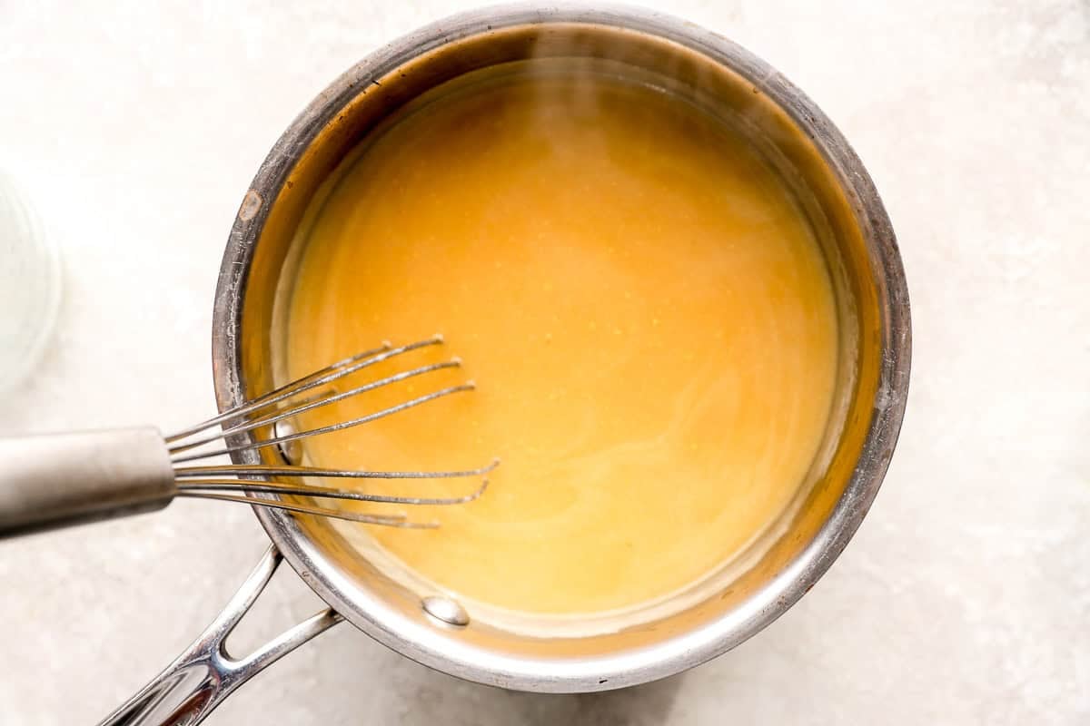 chicken broth gravy in a saucepan with a whisk.