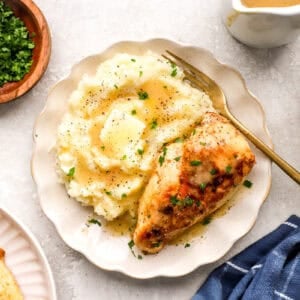 creamy chicken and mashed potatoes with gravy on a plate with a fork.