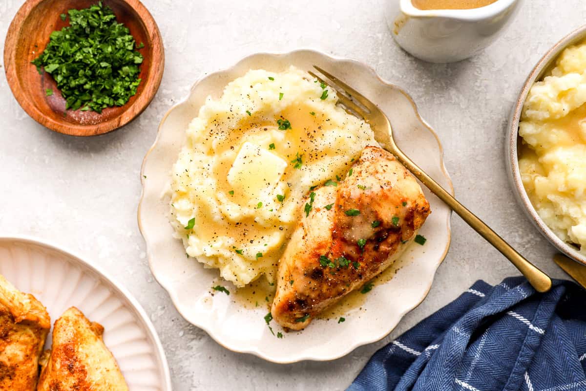 creamy Dijon chicken and mashed potatoes with gravy on a plate with a fork.