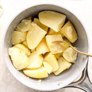 fork-tender quartered potatoes in a saucepan.