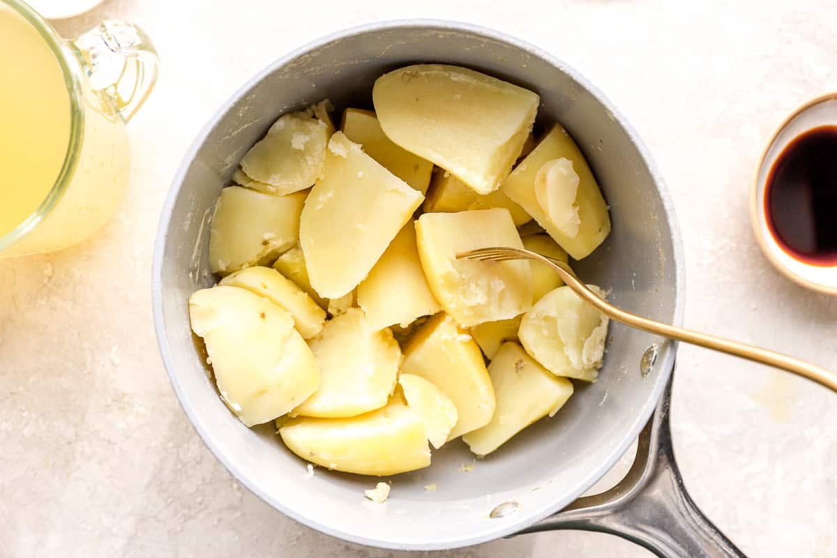 fork-tender quartered potatoes in a saucepan.