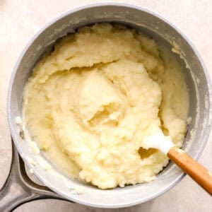 creamy mashed potatoes in a saucepan with a rubber spatula.