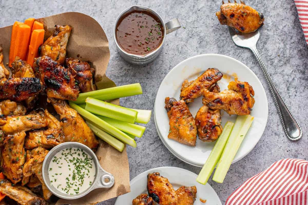 a serving of crockpot bourbon wings on a white plate with celery sticks.