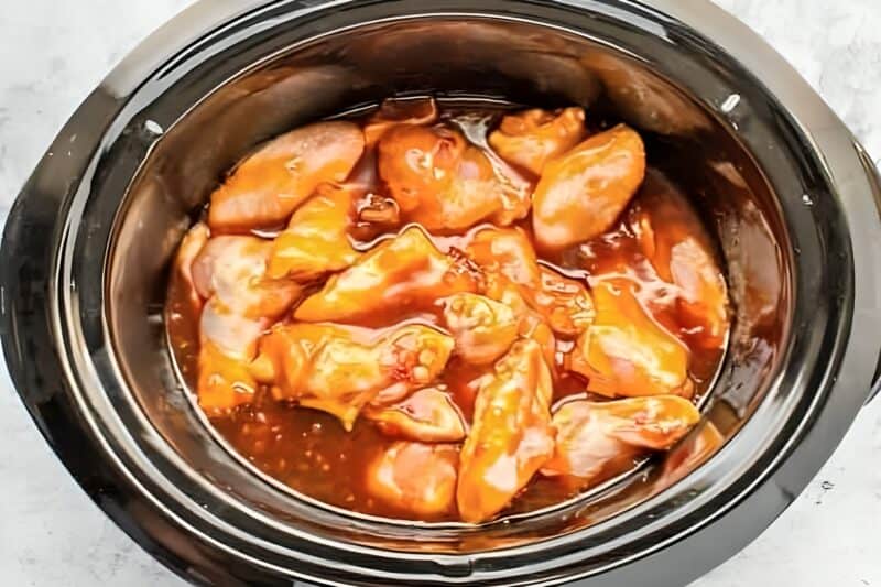 raw chicken wing portions and bourbon sauce in a crockpot.