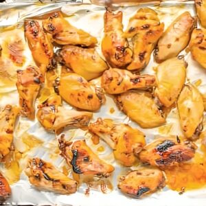 broiled bourbon chicken wings on a foil-lined baking sheet.