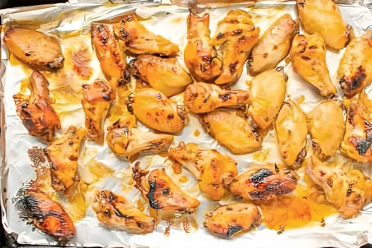 broiled bourbon chicken wings on a foil-lined baking sheet.