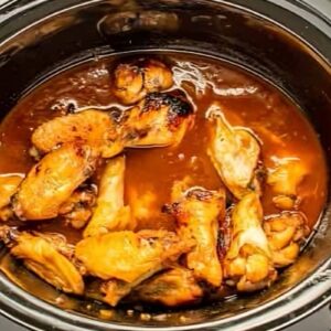 cooked and broiled chicken wings in bourbon sauce in a crockpot.
